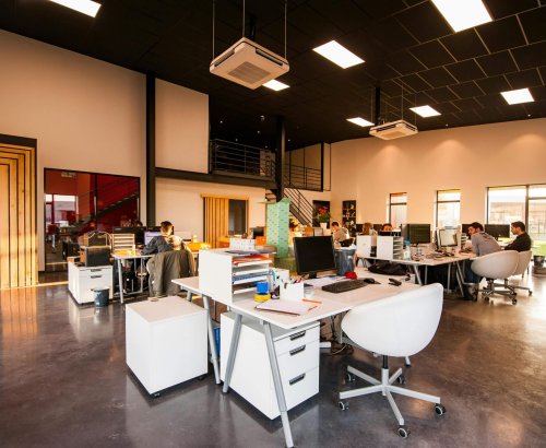 A spacious and modern open-plan office with natural lighting and employees working at desks.