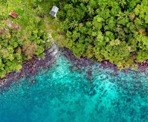 A stunning aerial view of Sukakarya's vibrant coast in Indonesia, featuring lush greenery and turquoise waters.
